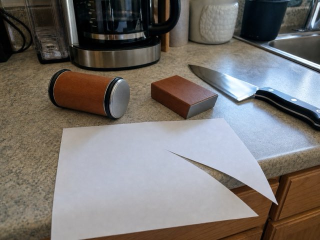 A sheet of printer paper cut cleanly, with the Keldley roller and angle block on the counter